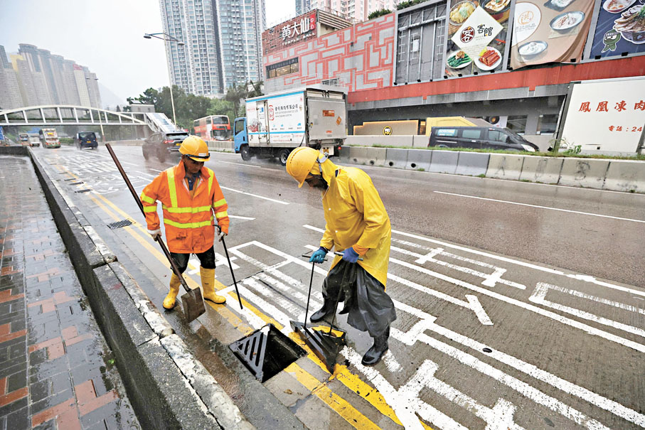 ●渠務署工作人員於路面渠位疏導積水。香港文匯報記者郭木又  攝
