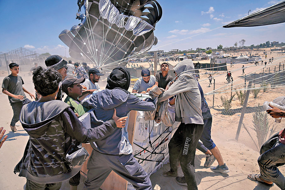 ●巴人爭相收集空投到加沙中部代爾巴拉赫的援助物資。美聯社