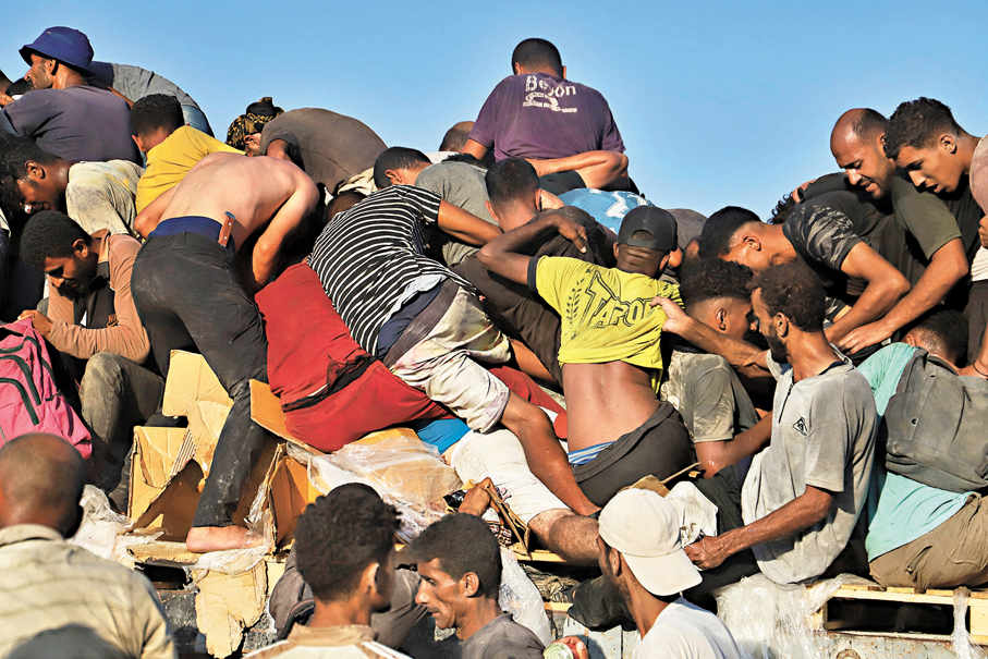 ●巴人湧上一輛滿載人道物資的貨車。 美聯社