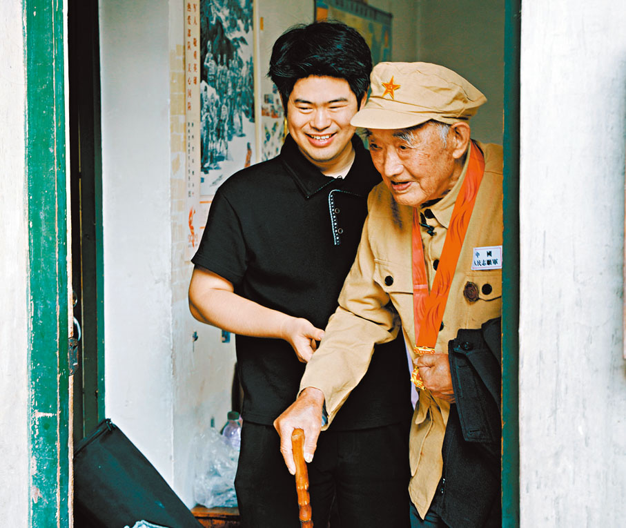 ●韓佳龍攙扶陝西漢中志願軍老兵王成福從臥室走到拍攝現場。