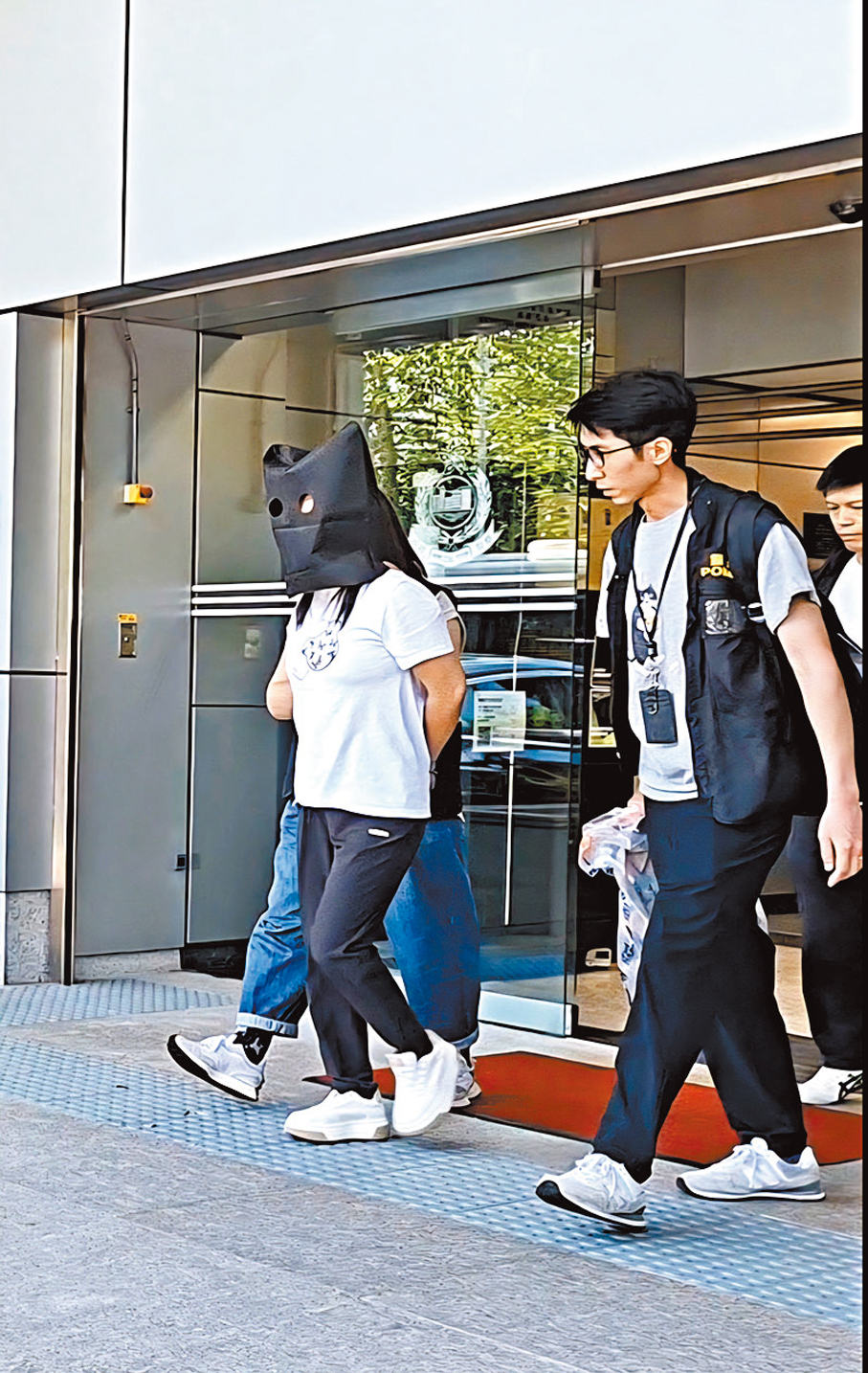 ●涉案詐騙集團一名女骨幹成員被黑布蒙頭，由探員押解返警署。