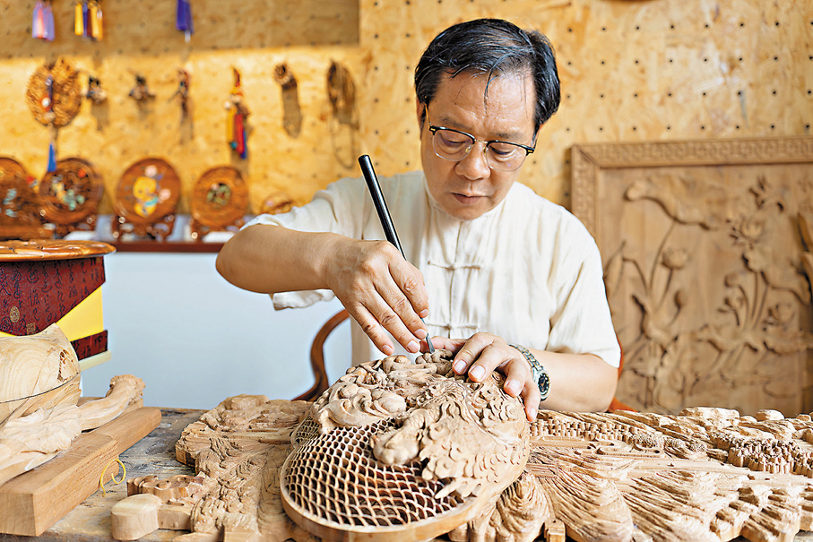 ●山東省非物質文化遺產桃木雕刻民俗代表性傳承人、「泰山桃木王」掌門人王來新在雕刻桃木直播帶貨。 記者胡臥龍  攝