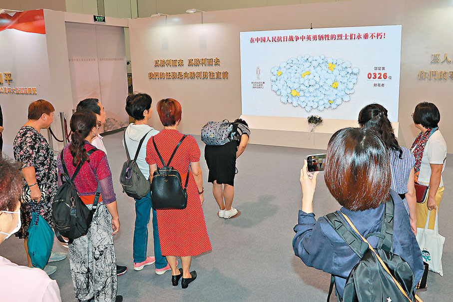 ●觀眾在獻花電子屏前鞠躬致意。 香港文匯報記者北山彥  攝