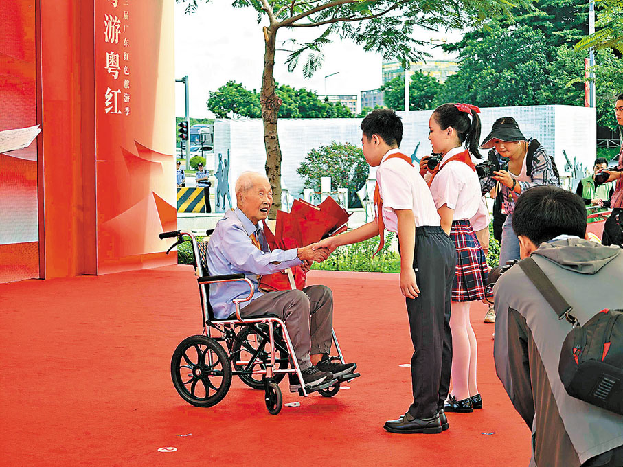 ●百歲東江縱隊抗戰老兵黎洪接受學生代表獻花。香港文匯報記者帥誠 攝