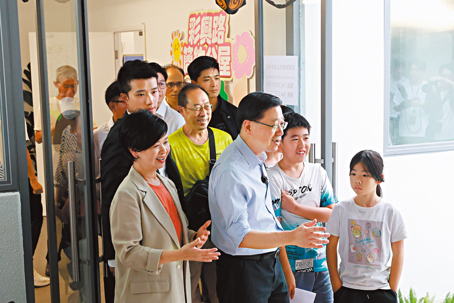 ●李家超探訪彩興路「簡約公屋」居民,與林先生一家邊走邊聊。 香港文匯報記者北山彥 攝