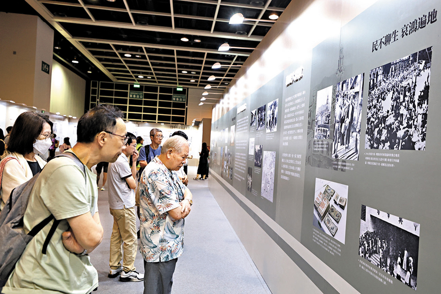 ●梁先生（前排長者）參觀展板，憶兒時逃難情景。 香港文匯報記者萬霜靈  攝