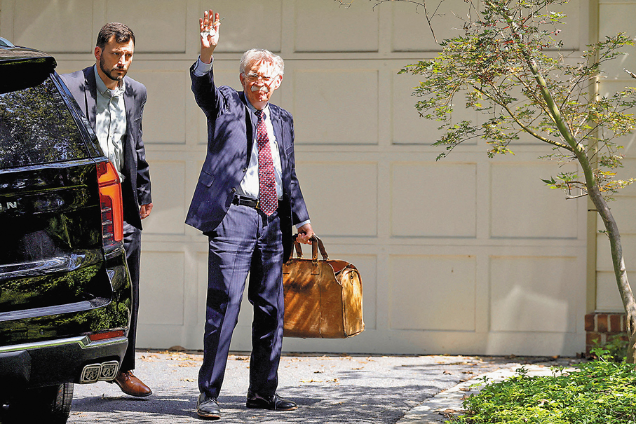 ●博爾頓在FBI搜查後返回其住所，向在場記者揮手。 路透社