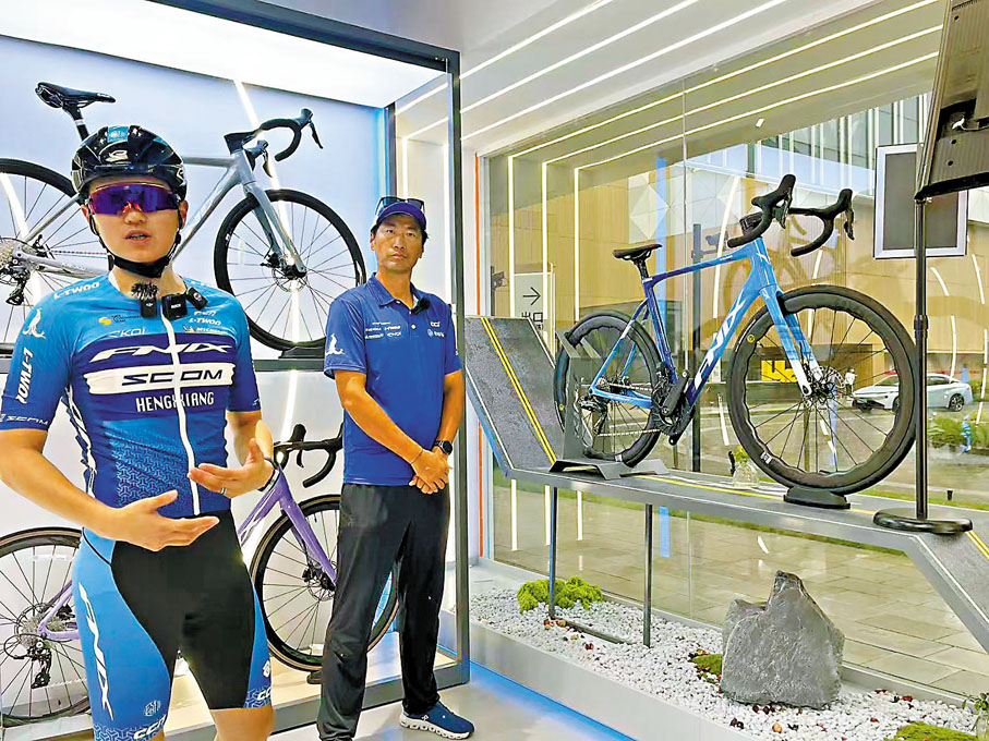 ●李富玉（左）與上海鳳凰自行車有限公司副總裁薛佳琛（右）介紹比賽用車及備賽情況。  香港文匯報記者夏微  攝