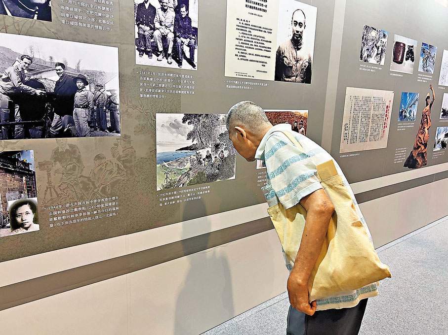 ●88歲的陳老伯仔細看展覽，他強忍傷痛向記者憶述被戰火毀掉的童年。香港文匯報記者康敬  攝