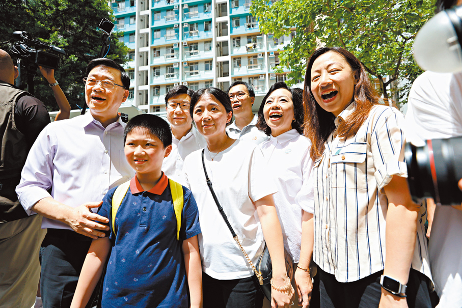 ●李家超（左一）與劉子軒小朋友（左二）及其母親方女士合照。兩母子大讚特首「好好人！」 香港文匯報記者萬霜靈  攝