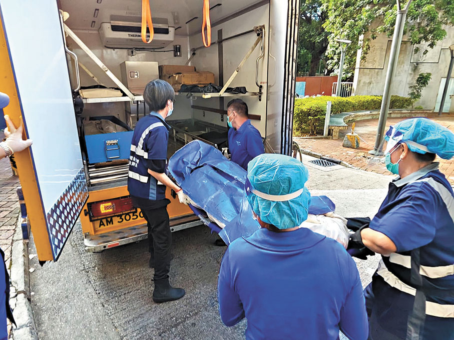 ●仵工將母子遺體舁送殮房。香港文匯報記者劉友光  攝