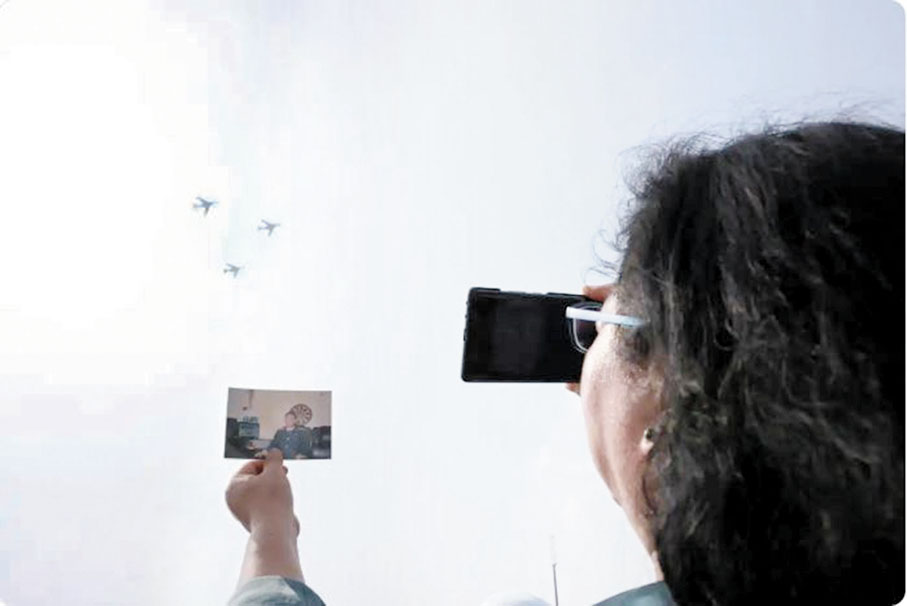 ●9月3日，空中梯隊飛過天安門廣場時，王偉的妻子阮國琴在觀禮台上把王偉的照片舉向藍天。 網上圖片    