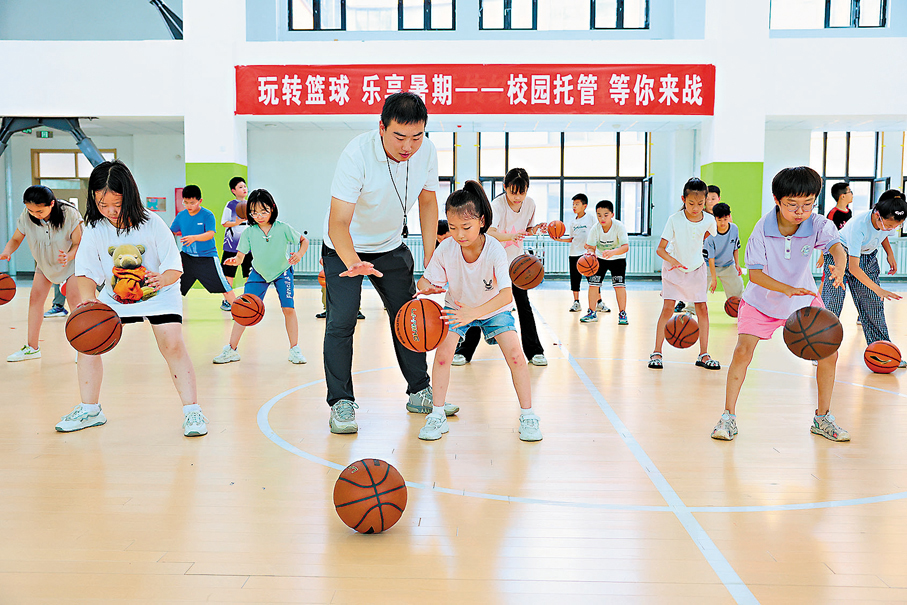 ●小學提供暑期託管服務，學生在老師指導下練習籃球基本功。 資料圖片