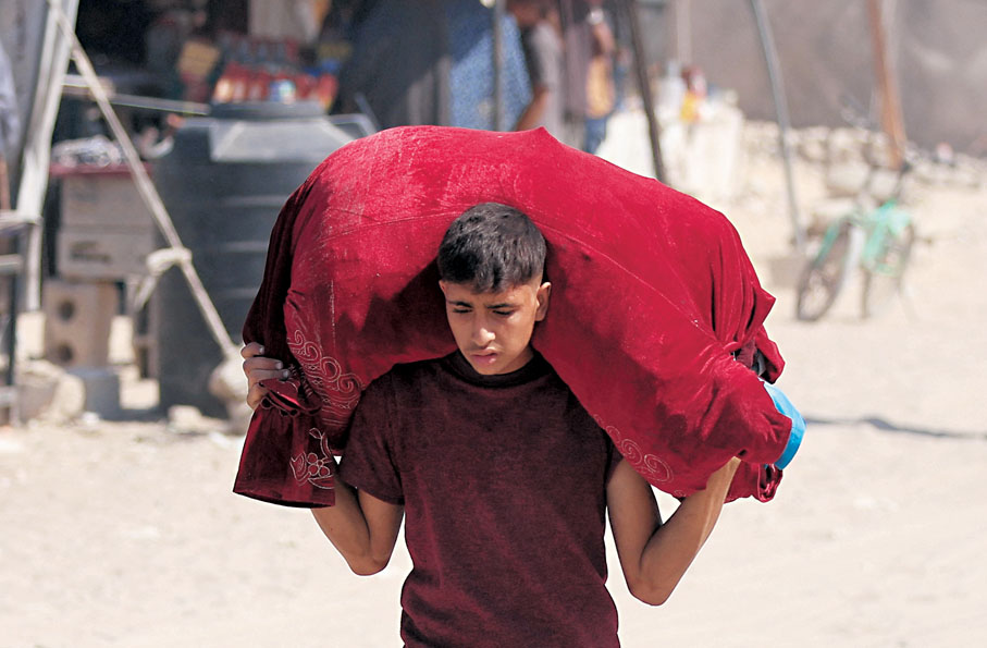 ●加沙城一名流離失所的巴人手持財物撤離。路透社
