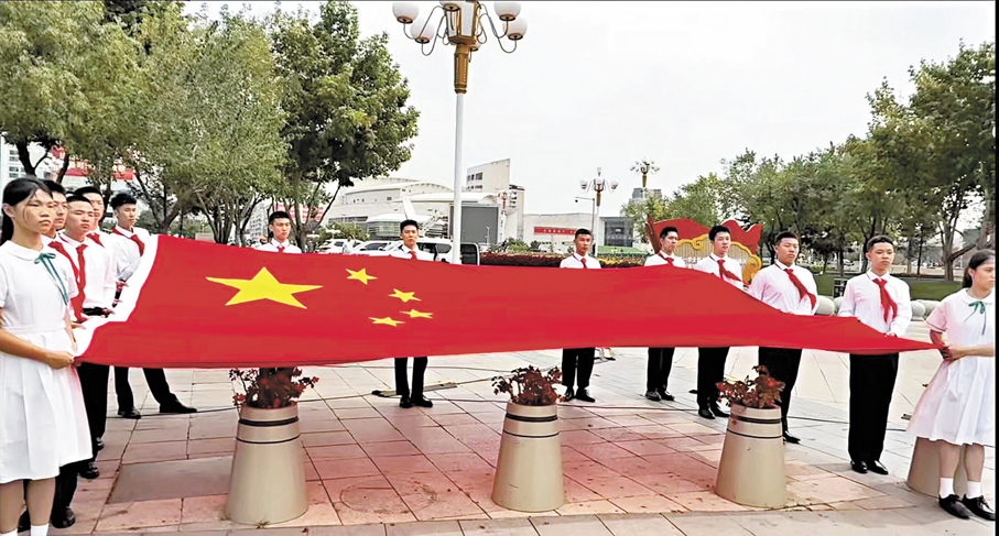 ●來自遼寧、香港兩地的學子在瀋陽人民廣場，向護送烈士遺骸棺槨車隊展示這面特殊寓意的五星紅旗。 香港文匯報實習記者何思熳  攝