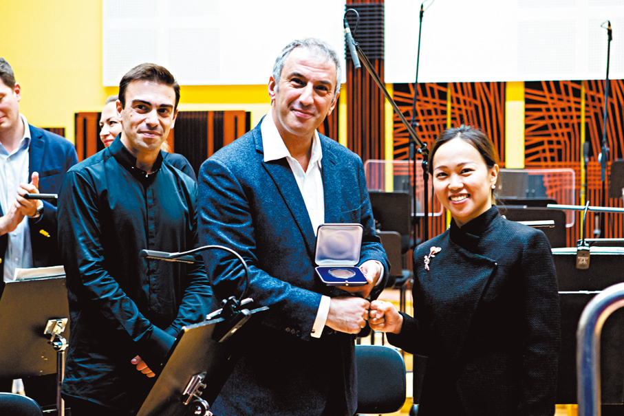 ●葉詠媛（右）從費力西國際指揮大賽藝術總監Michael Zukernik（中）手中接過獎牌。 港中大供圖