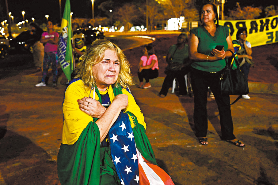 ●披上巴西及美國國旗的博爾索納羅支持者傷心痛哭。 法新社
