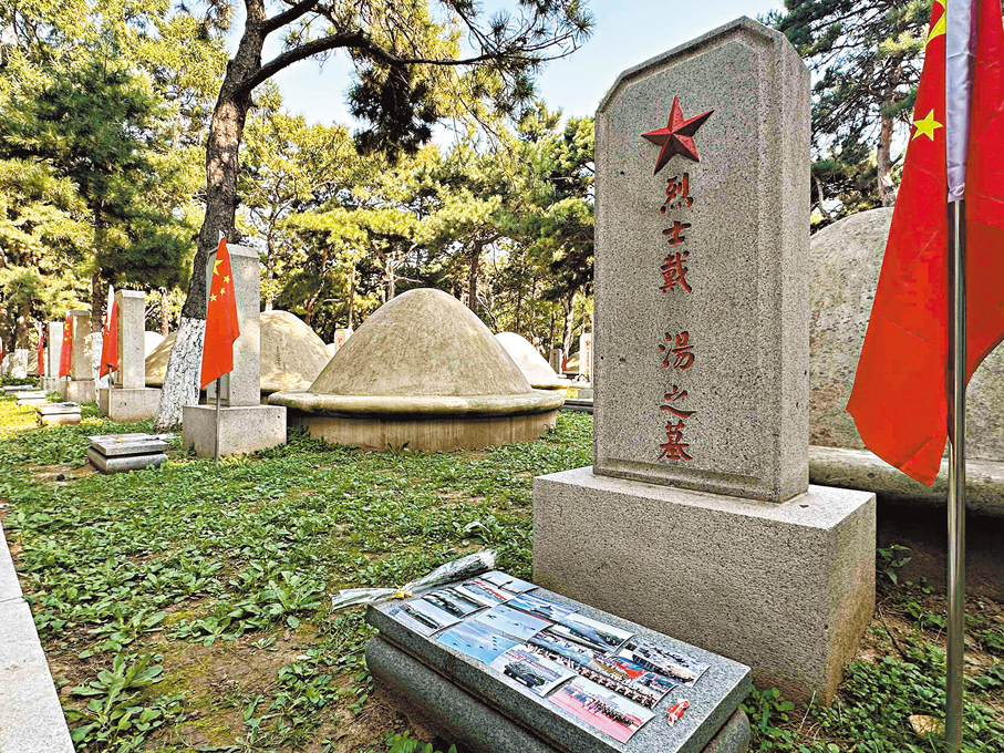 ●在烈士戴湯的墓碑前，九三閱兵的高清照片整齊排列。