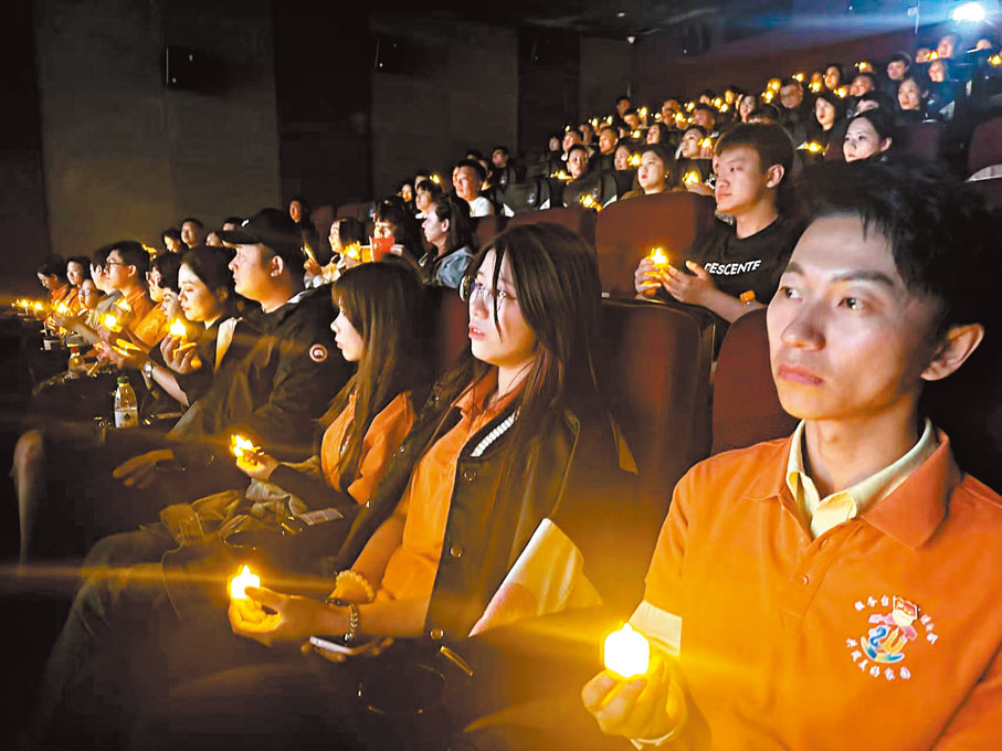 ●觀眾手持蠟燭含淚觀影。香港文匯報記者王欣欣 攝