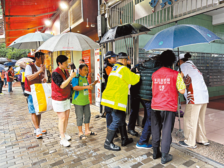 ●關愛隊雨中協助居民。 香港文匯報記者黃宇威  攝