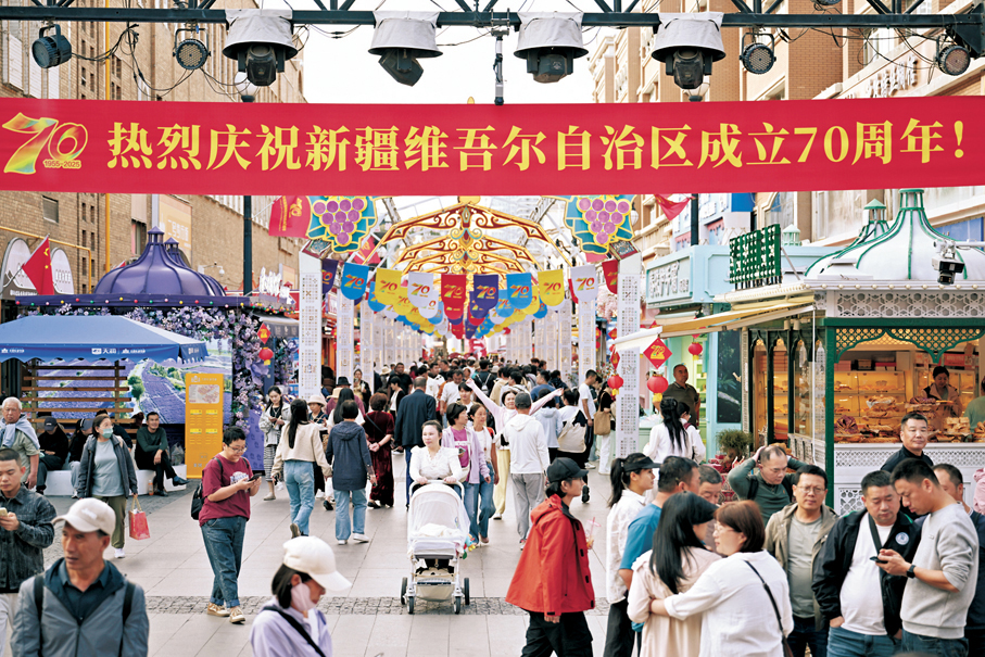 ●9月23日，遊客在新疆烏魯木齊市大巴扎步行街遊覽、拍照。為慶祝新疆維吾爾自治區成立70周年，烏魯木齊多處擺設花堆和宣傳牌等，街頭洋溢着喜慶祥和的氛圍。 中新社
