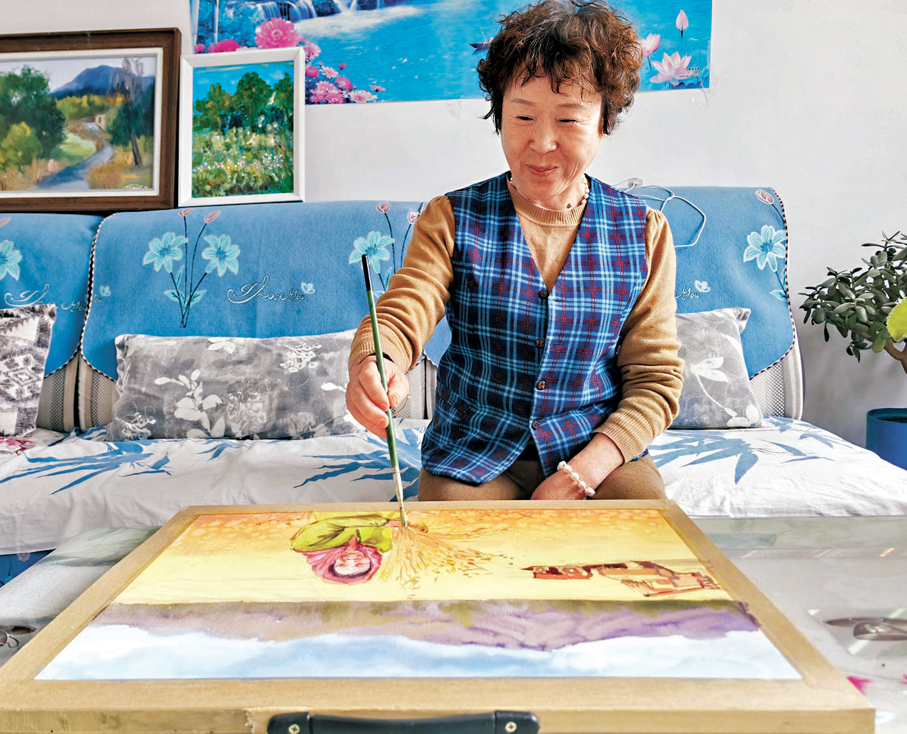 ●9月21日，新疆吉木薩爾縣新地鄉小分子村農民畫創作者張新香展示畫作《豐收》。 中新社