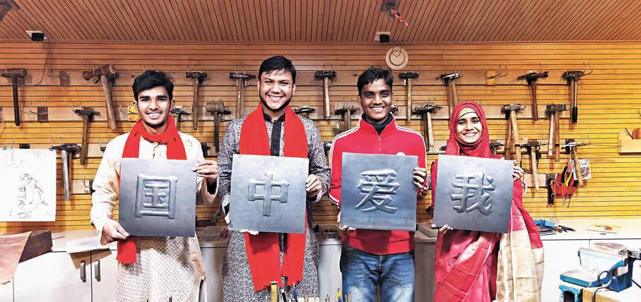 ●郭海博四位留學生弟子手持「我愛中國」鐵板浮雕作品合影留念。 受訪者供圖