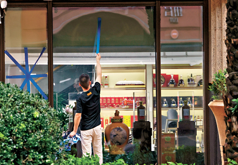 ●自9月24日16時起，深圳全市解除「五停」。圖為深圳南山區一名工作人員拆掉玻璃上的膠帶。 新華社