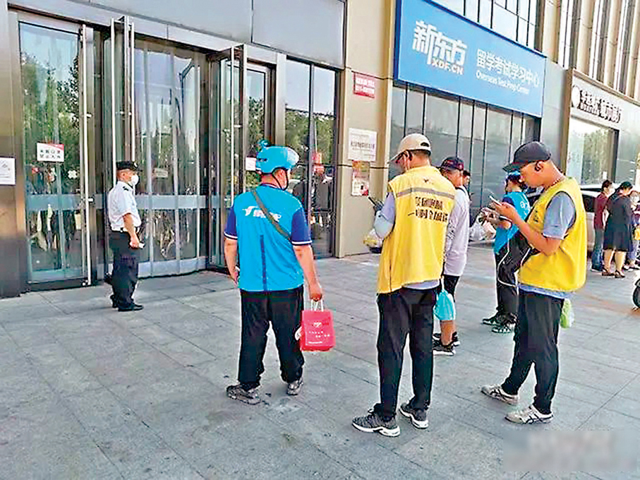 ●國家市場監督管理總局日前就《外賣平台服務管理基本要求（徵求意見稿）》正式面向社會公開徵求意見。圖為寫字樓下外賣員拿着外賣等待顧客下樓取餐。 資料圖片