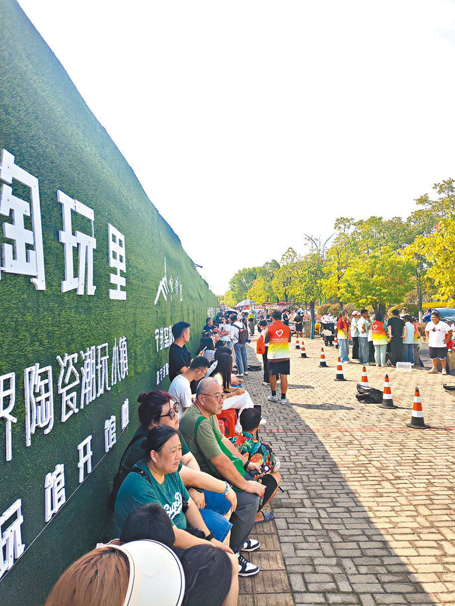 ●遊客們早早坐在板凳上排隊。香港文匯報記者黃慧  攝