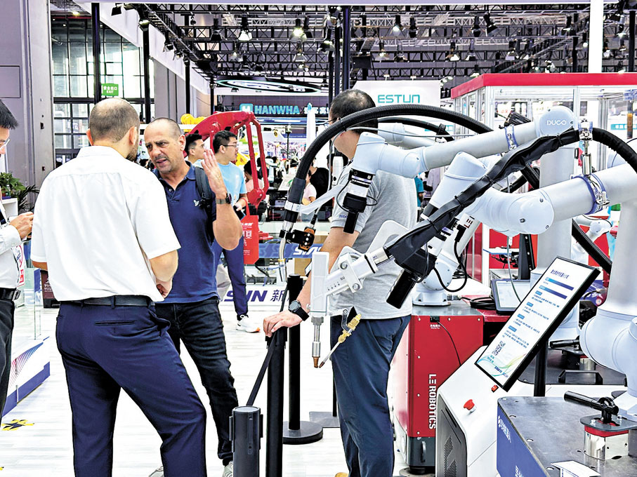 ●外商在展會上討論着中國產的機器人。
