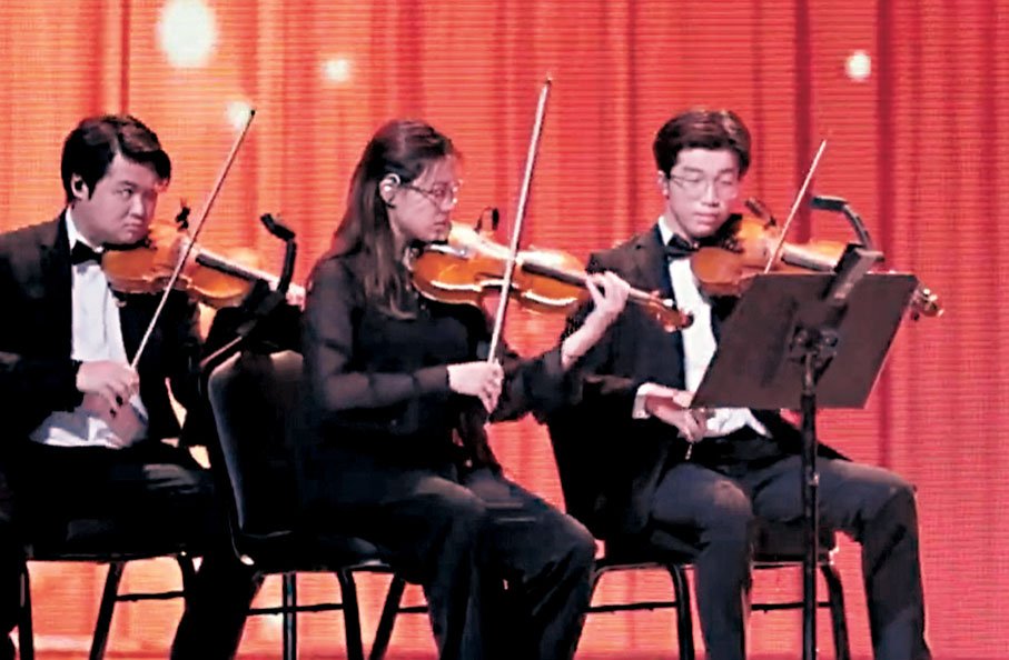 ●中五學生李靖甫（右）在2025年國慶文藝晚會中，以樂團團員身份踏上紅館舞台，演奏跨界作品《粵劇幻想曲》。李家超Fb片段截圖