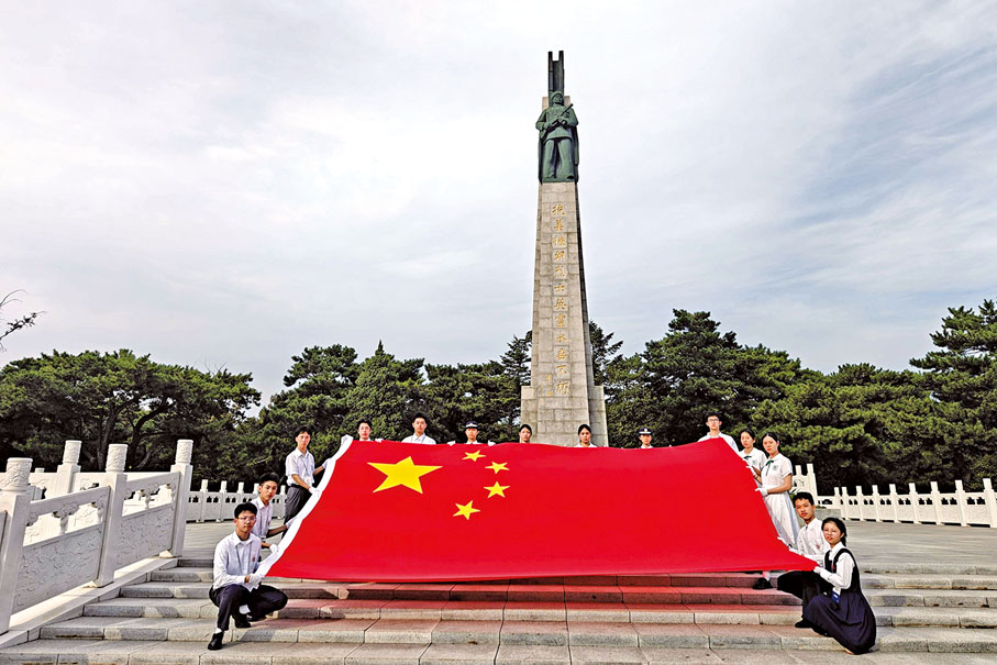 ●港澳學生代表在烈士陵園紀念碑前共同展示國旗。（澳門教青局圖片）