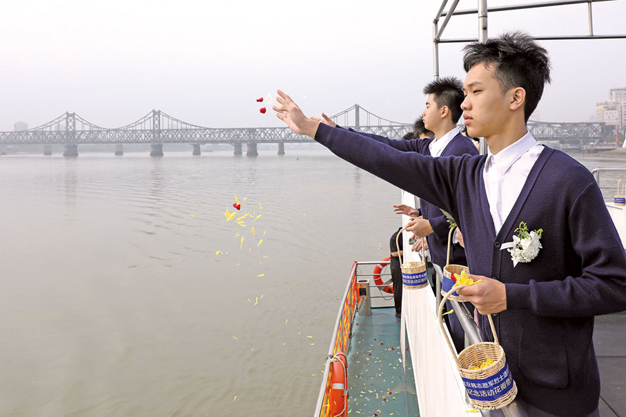 ●澳門學生代表在鴨綠江上播撒花瓣寄託哀思。（澳門教青局圖片）