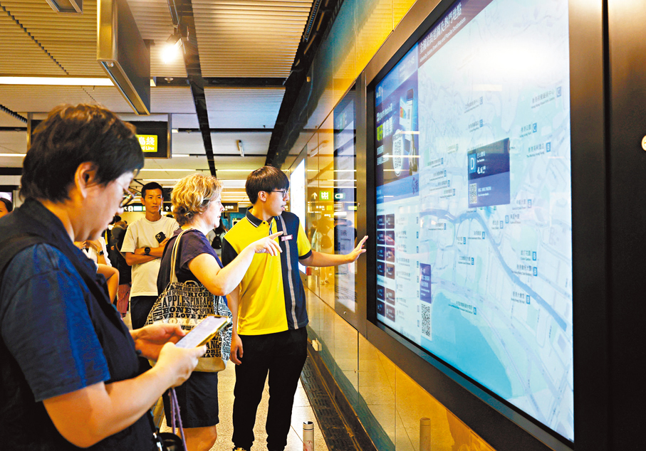 ●港鐵職員向乘客講解如何使用「電子街道圖及出口指示牌」。香港文匯報記者郭木又  攝