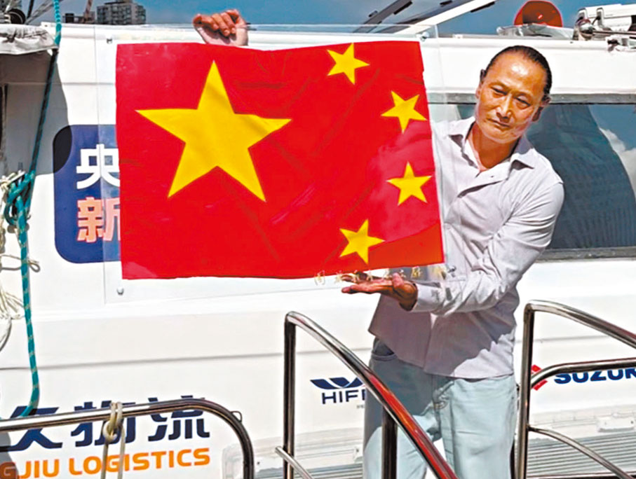 ●翟墨登船後向眾人展示五星紅旗。