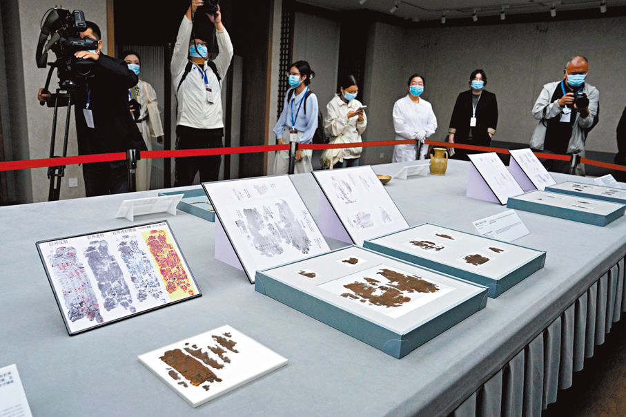 ●10月13日，媒體記者在湖南省博物館拍攝長沙子彈庫戰國帛書。圖為楚帛書《攻守占》殘片。 中新社