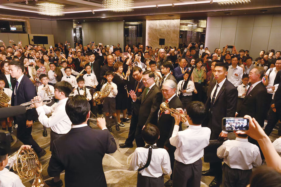 ●李家超在霍震霆、區永熙與一眾主禮嘉賓陪同下，於英華小學管樂團的演奏聲中進場。