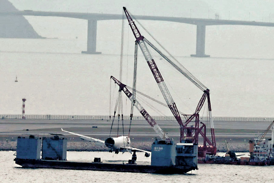 ●打撈船逐步將機身連機頭殘骸吊離水面，準備放上半潛船。 香港文匯報記者鄧偉明  攝