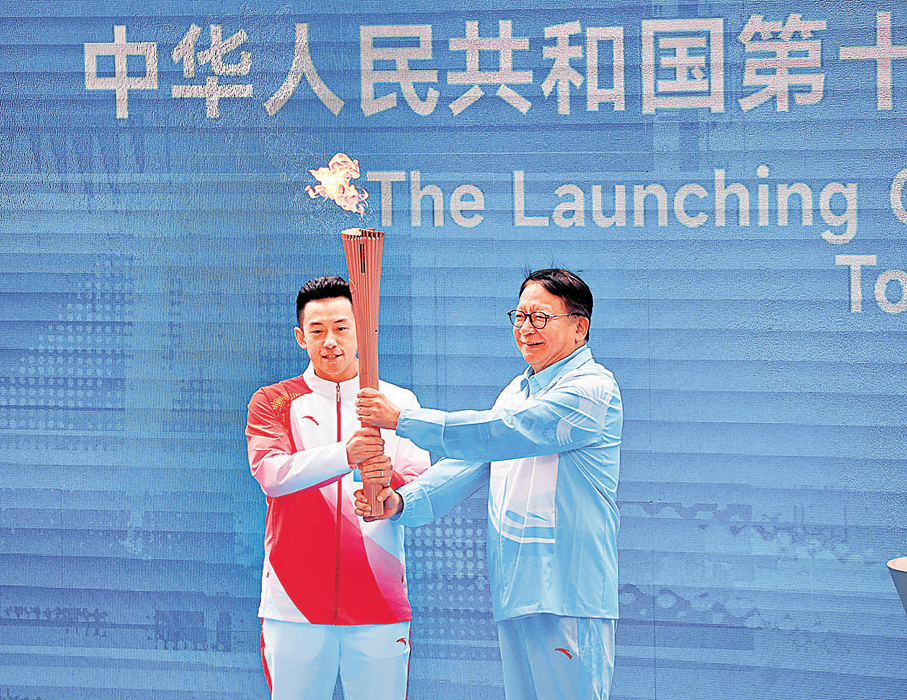 ●陳國基從聖火盆點燃第一支火炬後，交給第一棒火炬手黃鎮廷。 香港文匯報記者郭木又  攝
