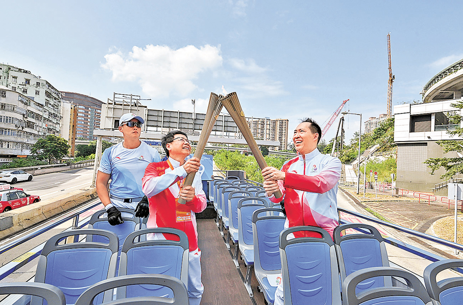 香港●第三十八棒火炬手黃永光（右）與第三十九棒火炬手鍾澤文（左）在開篷巴士上交接火種。