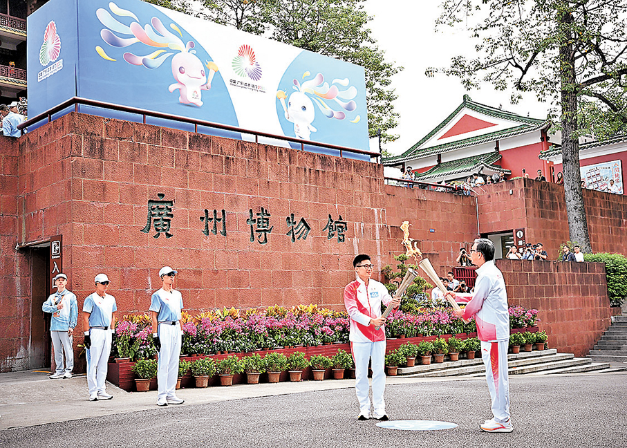 廣州●廣州火炬手楊景輝（左）、劉偉強在廣州博物館前交接火種。 新華社