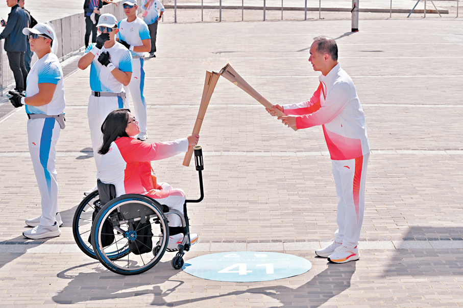 ●中電控股首席執行官及執行董事蔣東強（右）把火種傳給香港首名輪椅醫生呂慧翔（左）。