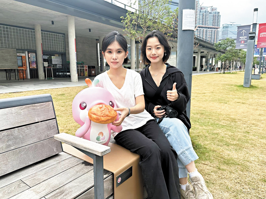 ●深圳遊客與拿着菠蘿包的「樂融融」合影，讚啟德的全運布置有香港特色。 香港文匯報記者郭正謙  攝