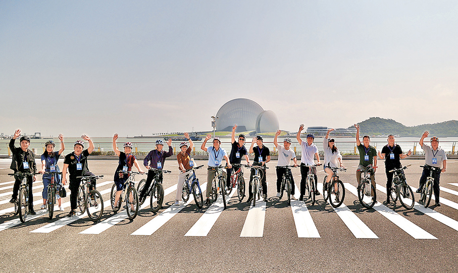●遊客在珠海情侶路騎行，背後就是珠海大劇院（日月貝）。