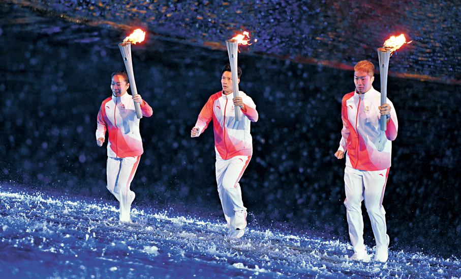 ●火炬手蘇炳添（中）、張家朗（右）、李禕在開幕式現場跑向主火炬。 新華社