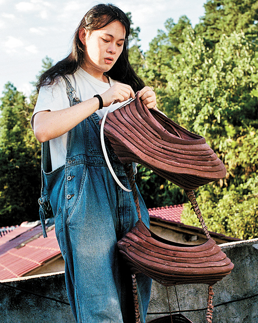 ●梁礫文在縫製衣服。  