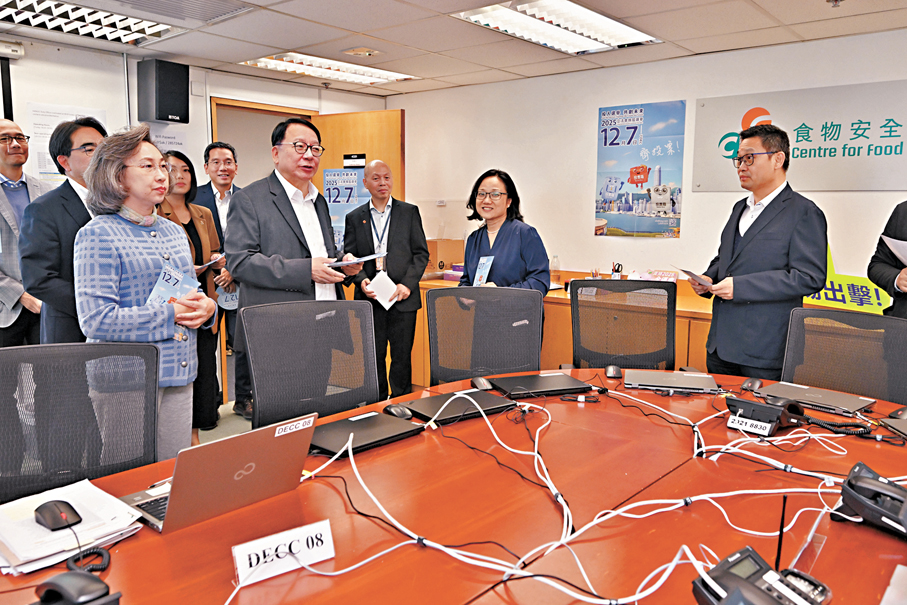 ●陳國基（左二）和楊何蓓茵（左一）在食物環境衞生署的工作間提醒同事與家人在12月7日立法會選舉中投票。