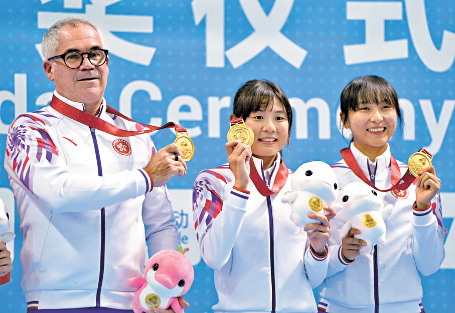 ●梁穎儀（中）、李思穎（右）及總教練達海飛展示金牌。 香港文匯報記者郭正謙 攝