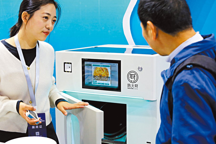 ●《方案》明確，鼓勵開發家庭服務機器人。圖為參會者在鄭州舉行的博覽會上了解智能炒菜機器人。 中新社